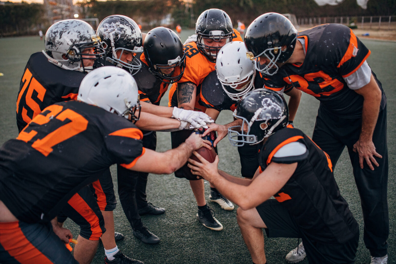 Team huddle reaching for football