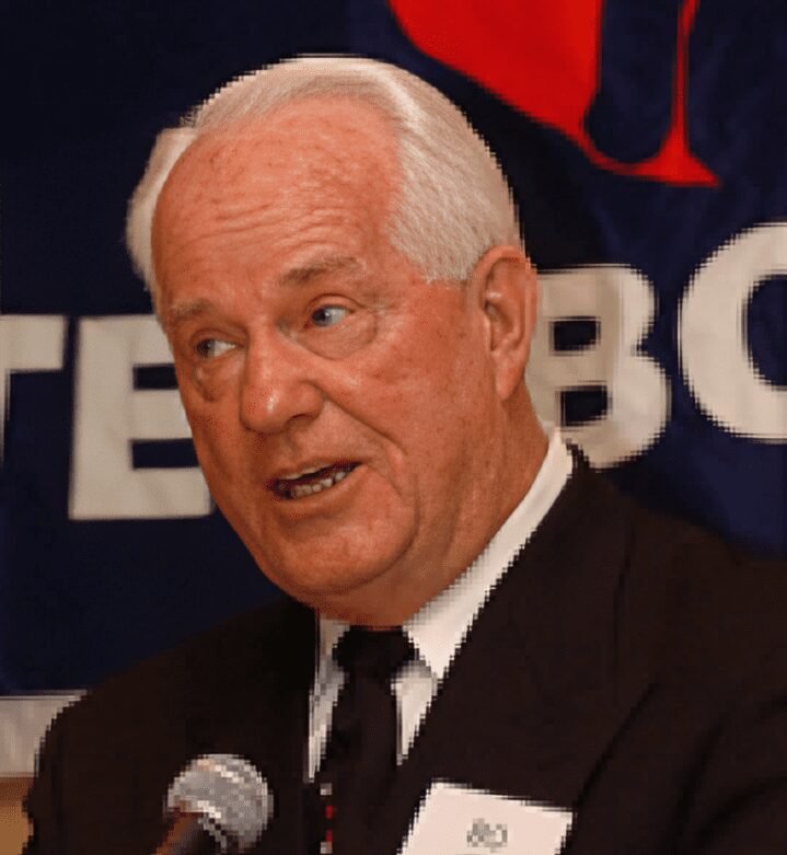 Older man in suit speaking into microphone