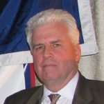 Man in suit and tie with flag backdrop
