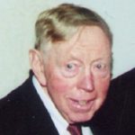 Elderly man in suit smiling at camera