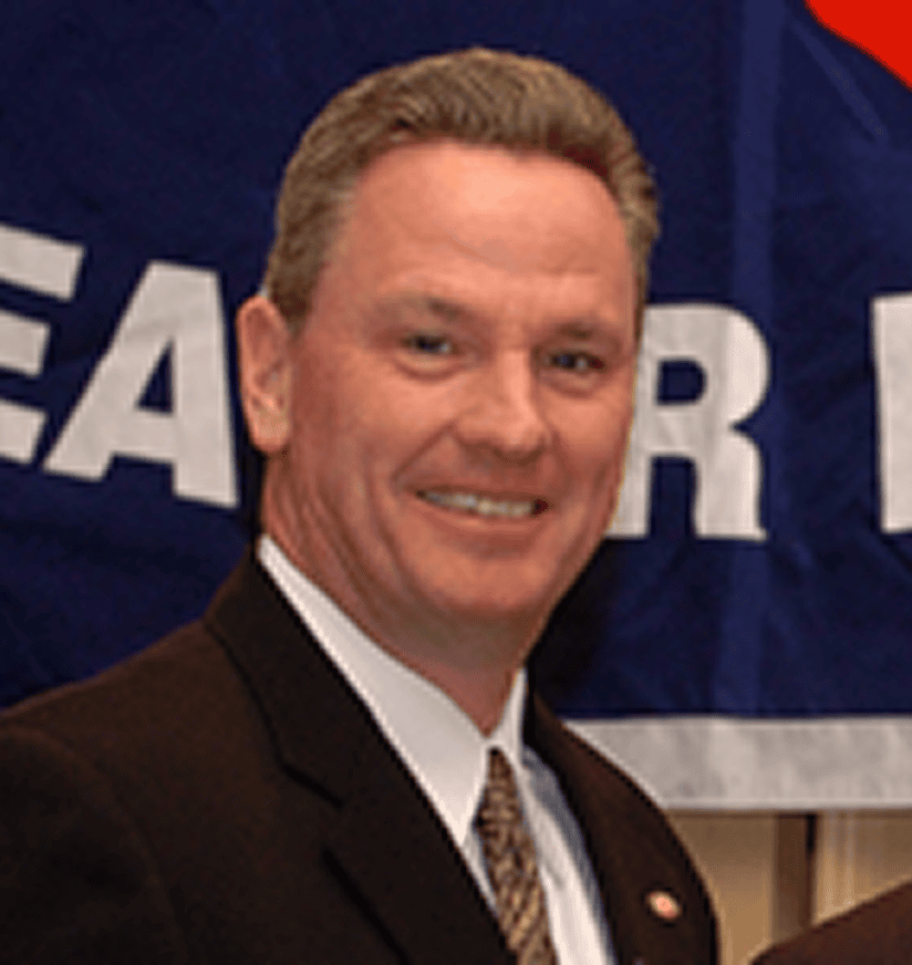 Smiling man in suit in front of banner