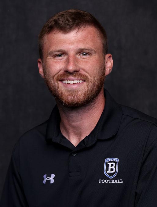 Smiling man in black football polo