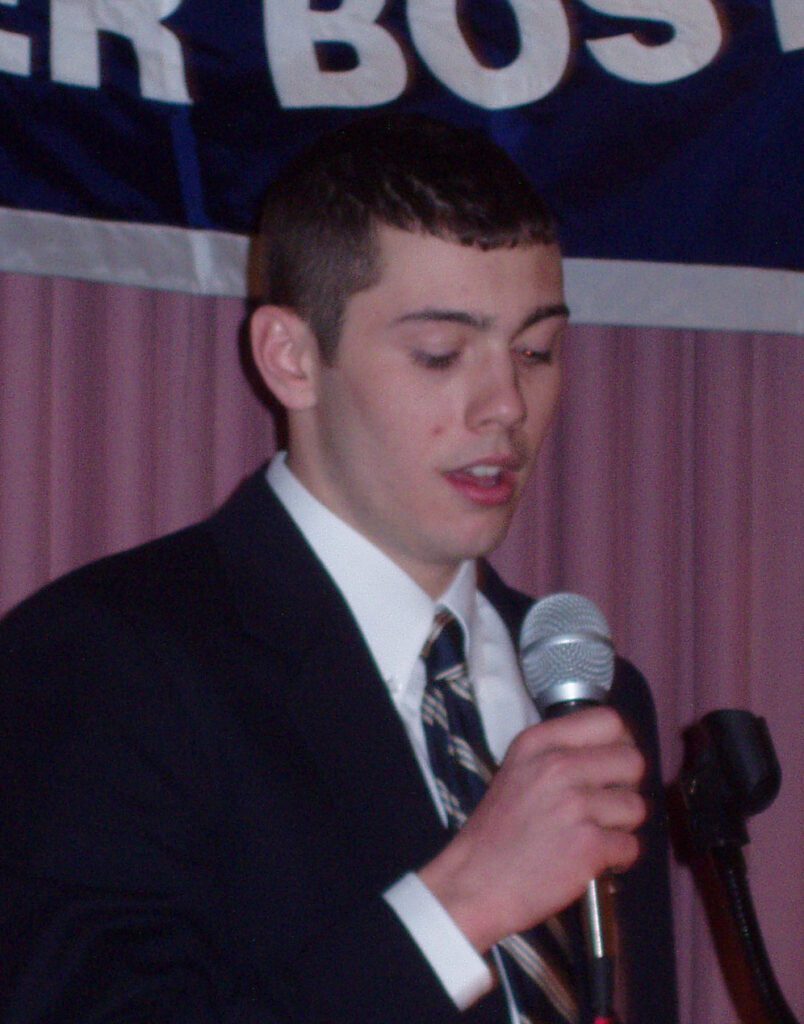 Young man in suit speaking into microphone