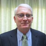 Man wearing suit, green tie, glasses