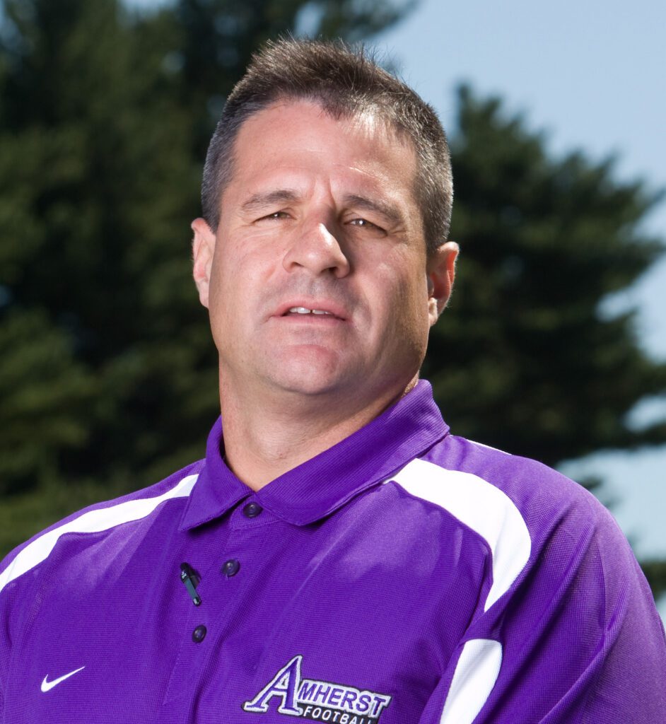 man wearing purple Amherst football polo