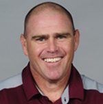 Smiling bald man in maroon collared shirt