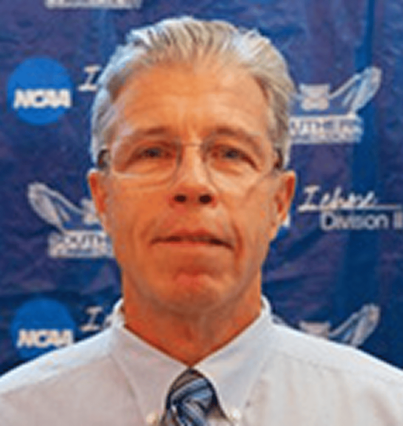 Man in glasses and tie with NCAA backdrop
