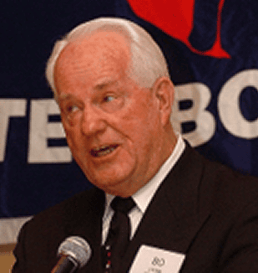 Elderly man speaking into microphone at podium