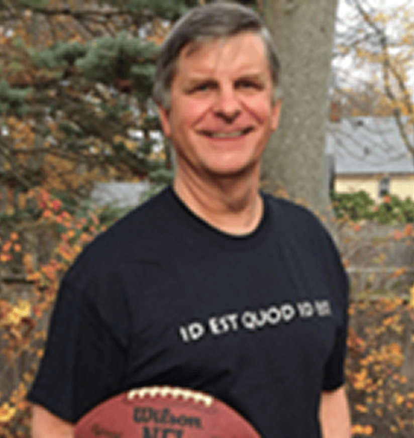 Smiling middle-aged man holding football outdoors