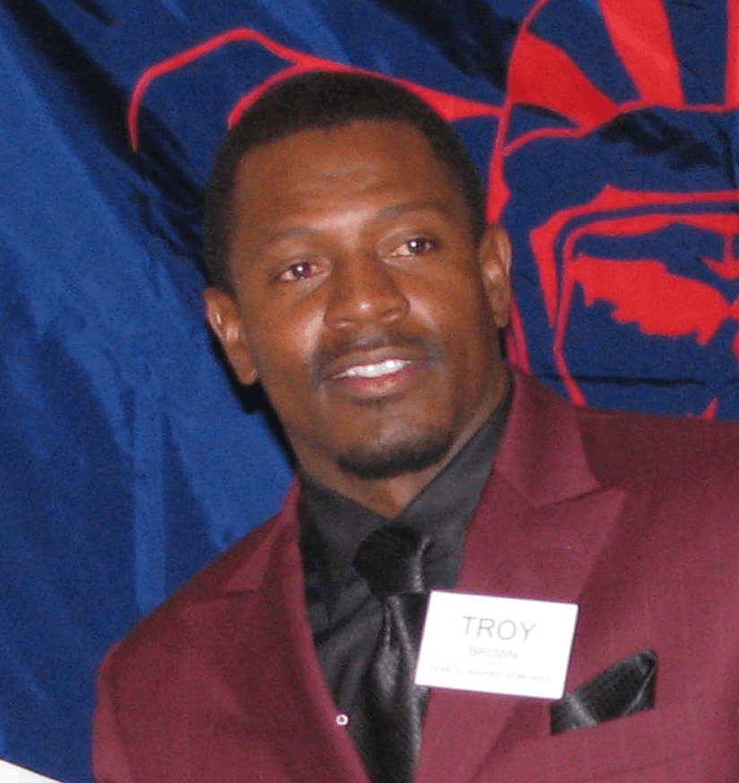 Smiling man in maroon suit with nametag