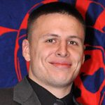 Smiling man in suit against red patterned backdrop